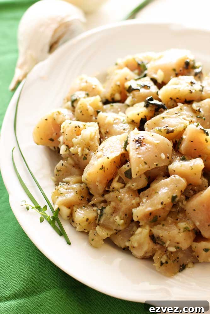 White plate containing Garlic Basil Chicken marinated in a secret sauce, topped with fresh thyme.