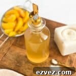 Peach Simple Syrup in a bottle with peaches in a mesh strainer
