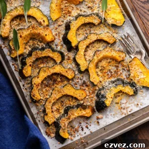 Parmesan roasted acorn squash on baking sheet with fork and blue napkin.