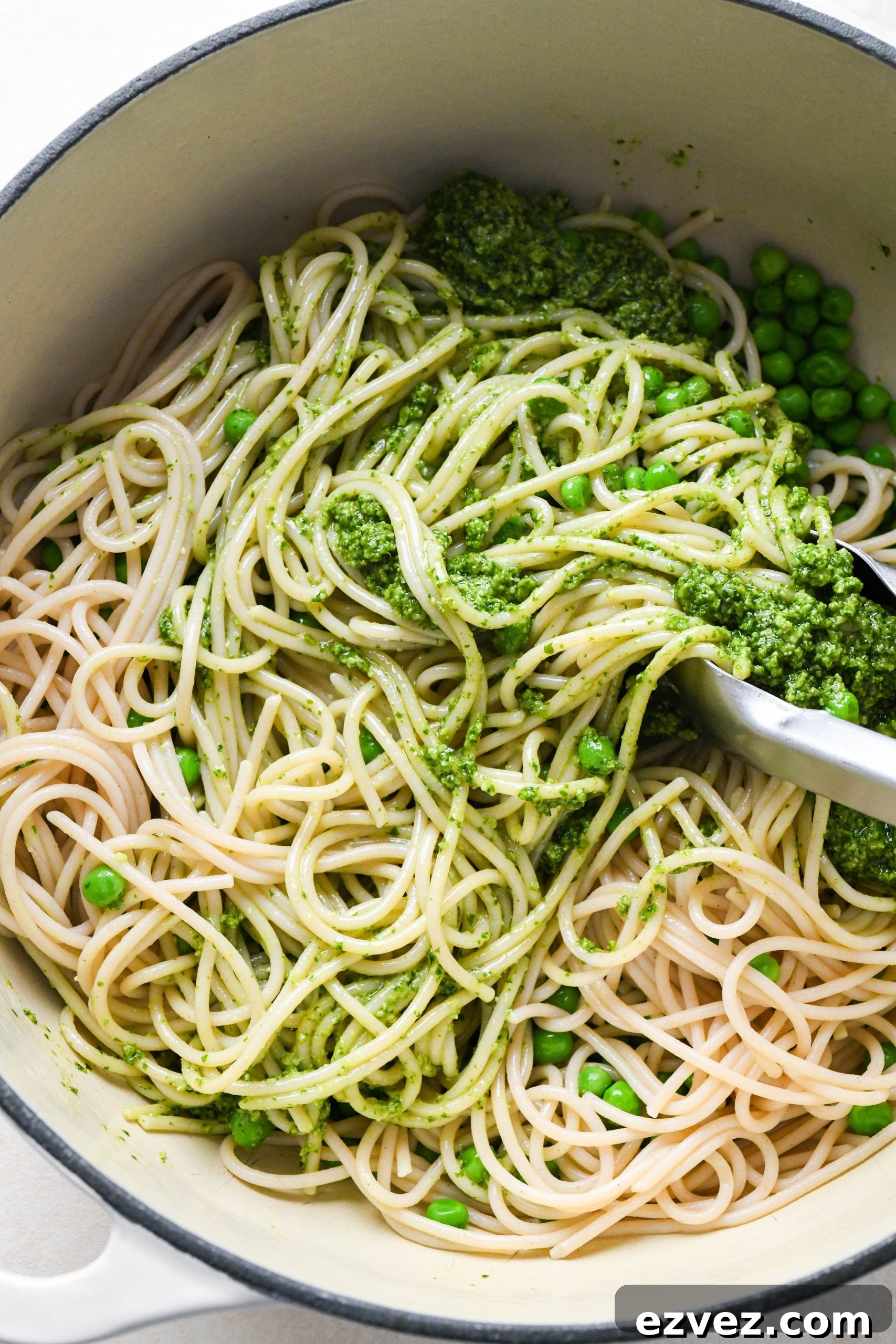 How to make easy pesto pasta: Tossing pasta together with sauce.