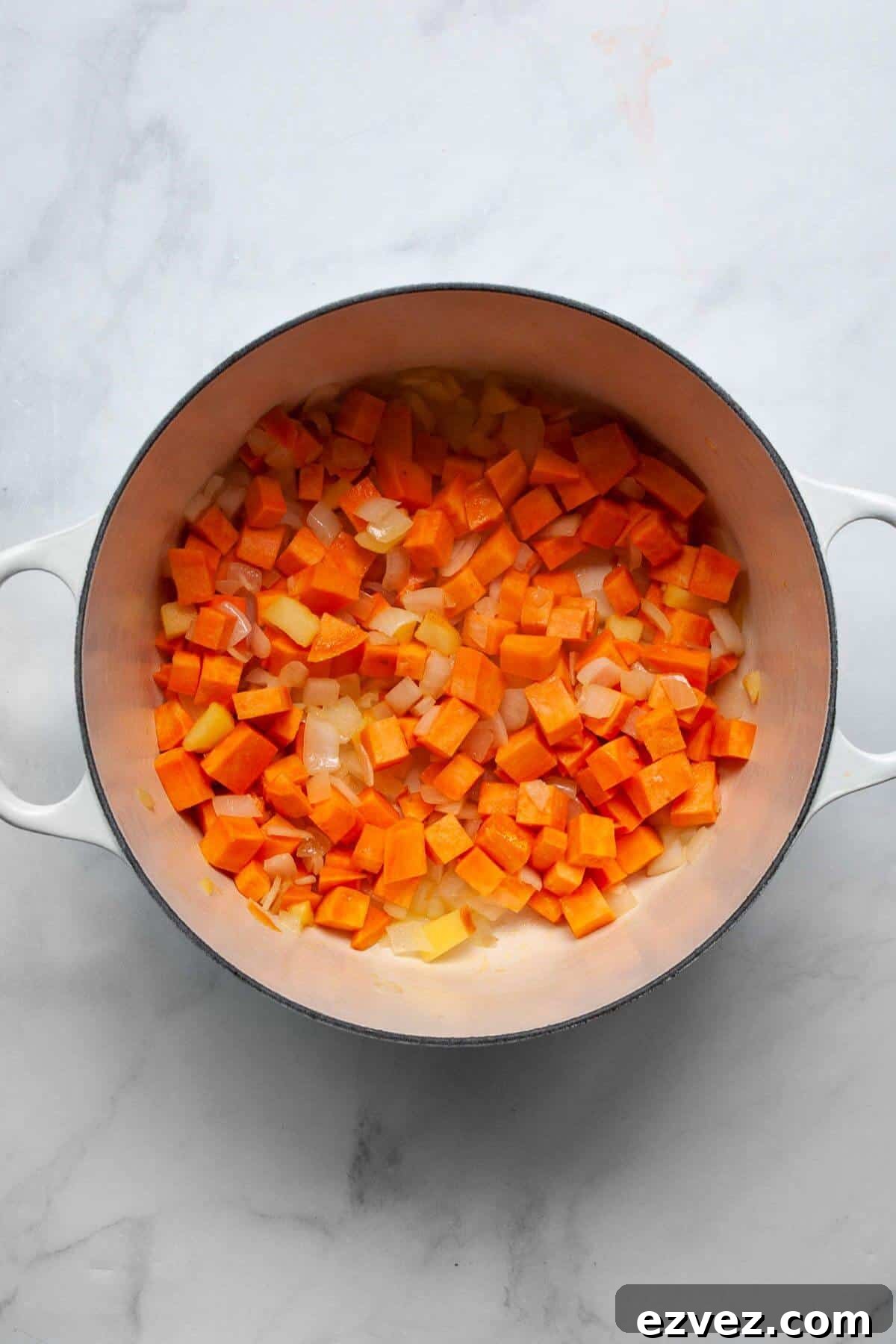 Sautéing chopped sweet potato, onion, and apple in a Dutch oven to start pumpkin sweet potato soup.