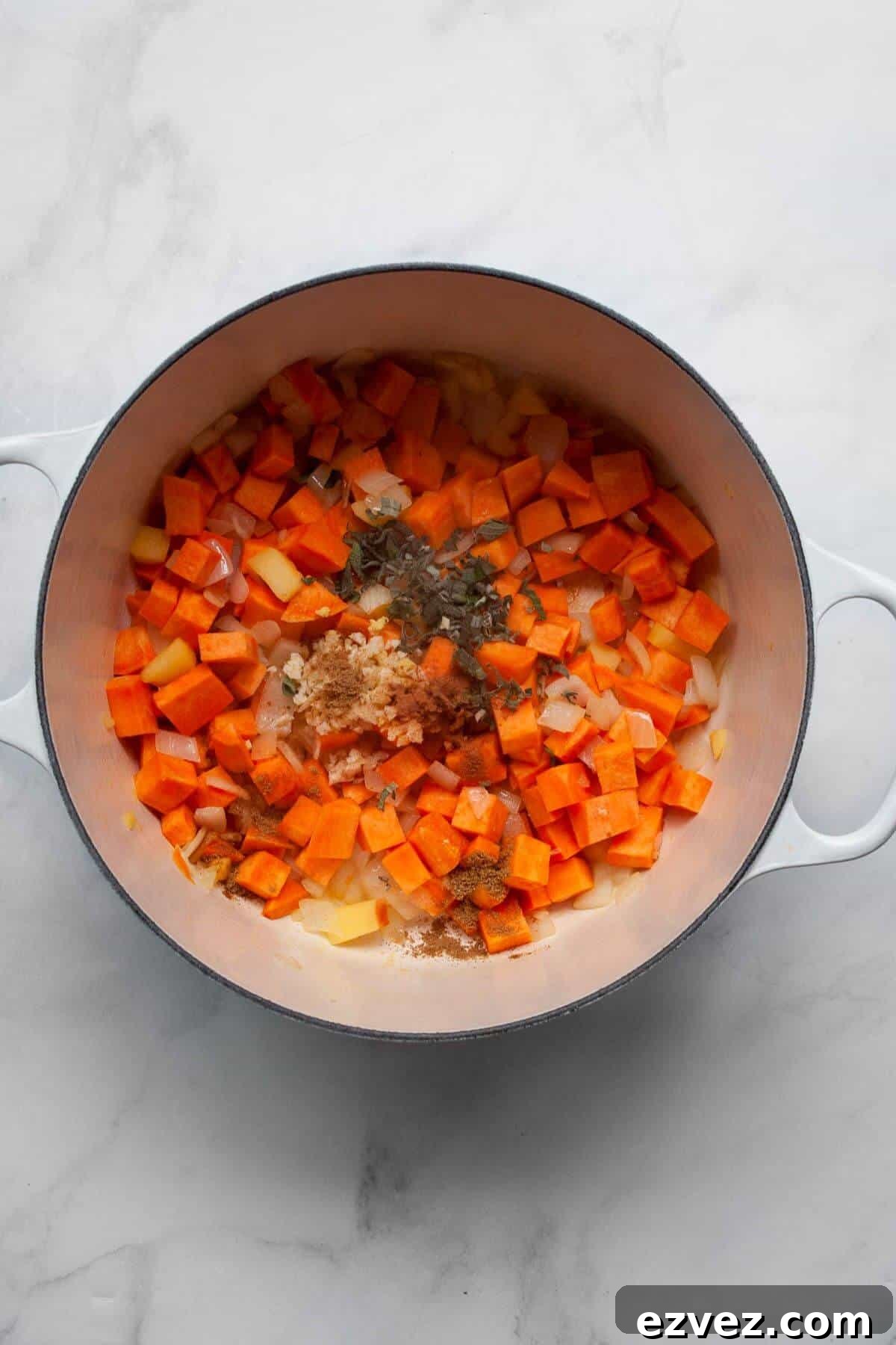 Adding fresh ginger, sage, and spices to the sautéing onions, apple, and sweet potato cubes.