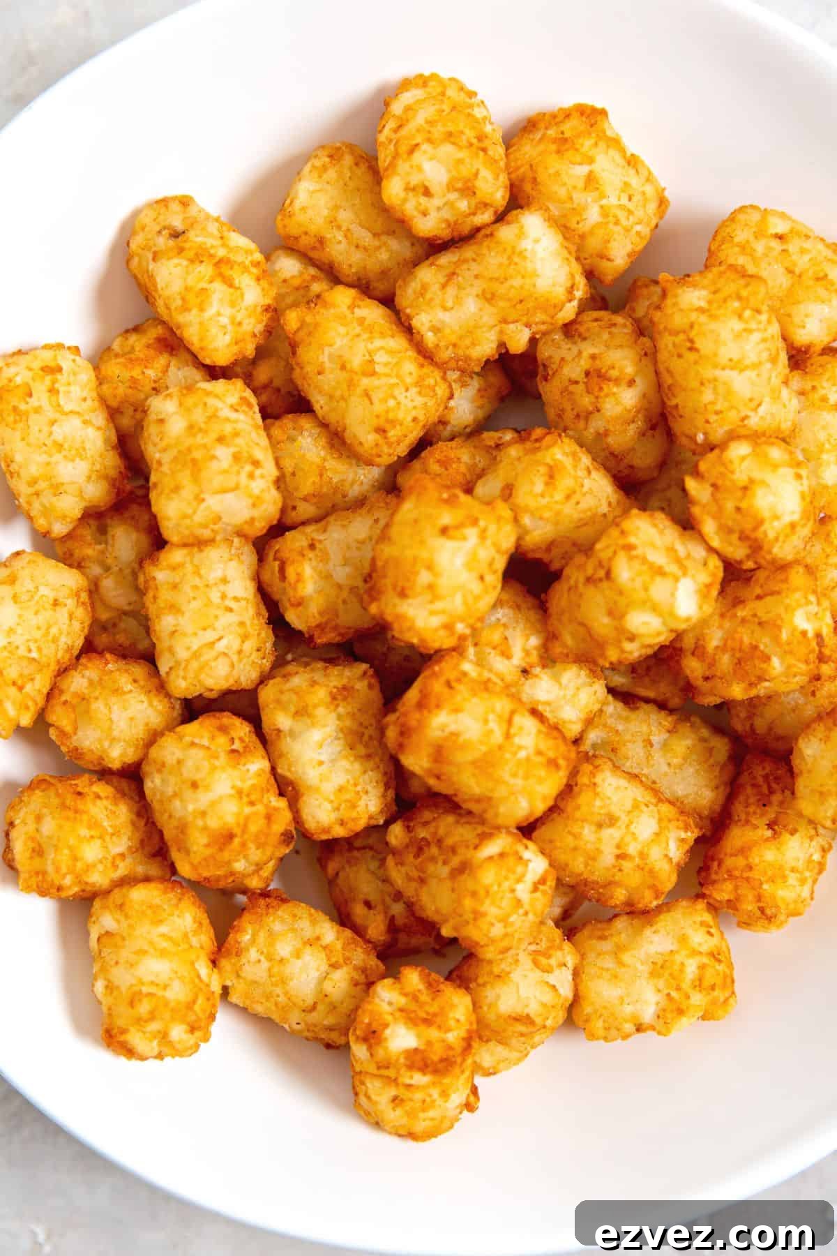 Freshly cooked air fryer tater tots in a white bowl.