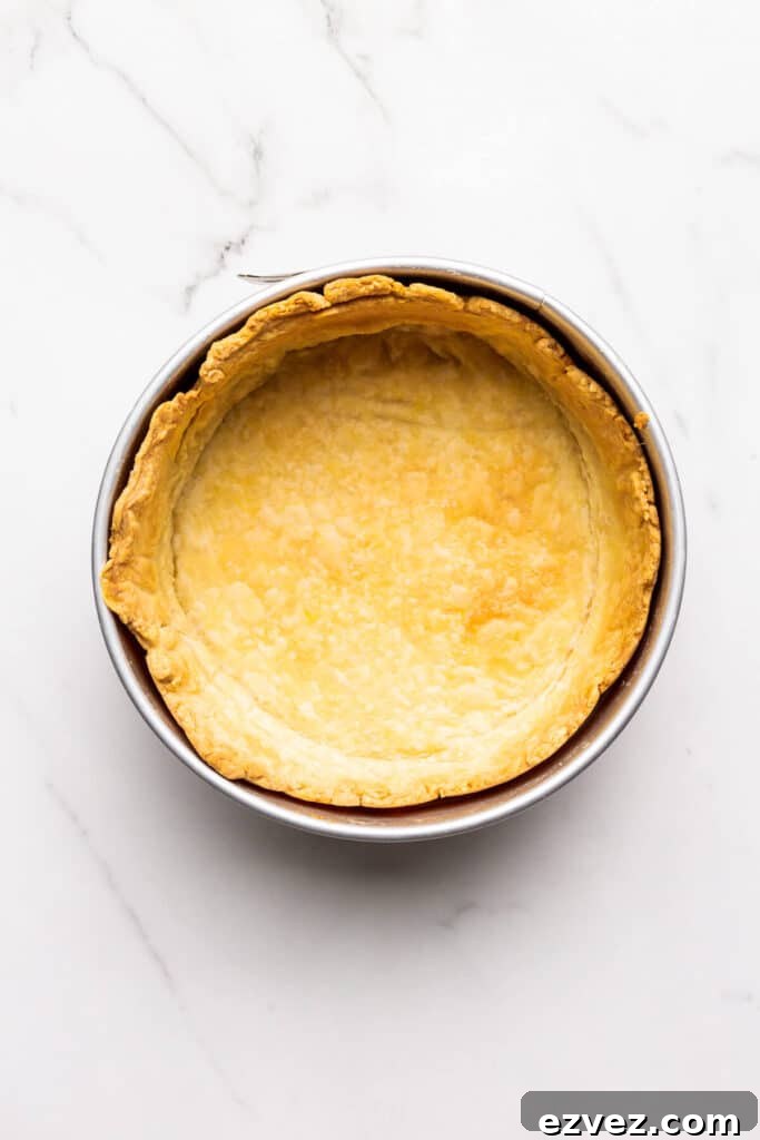 A blind baked pie crust in a 9 inch springform pan ready to be filled for a deep dish quiche.