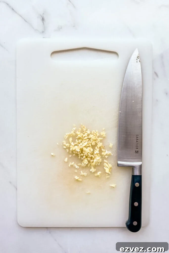 Chopping garlic on a white cutting board with a Chef knife.