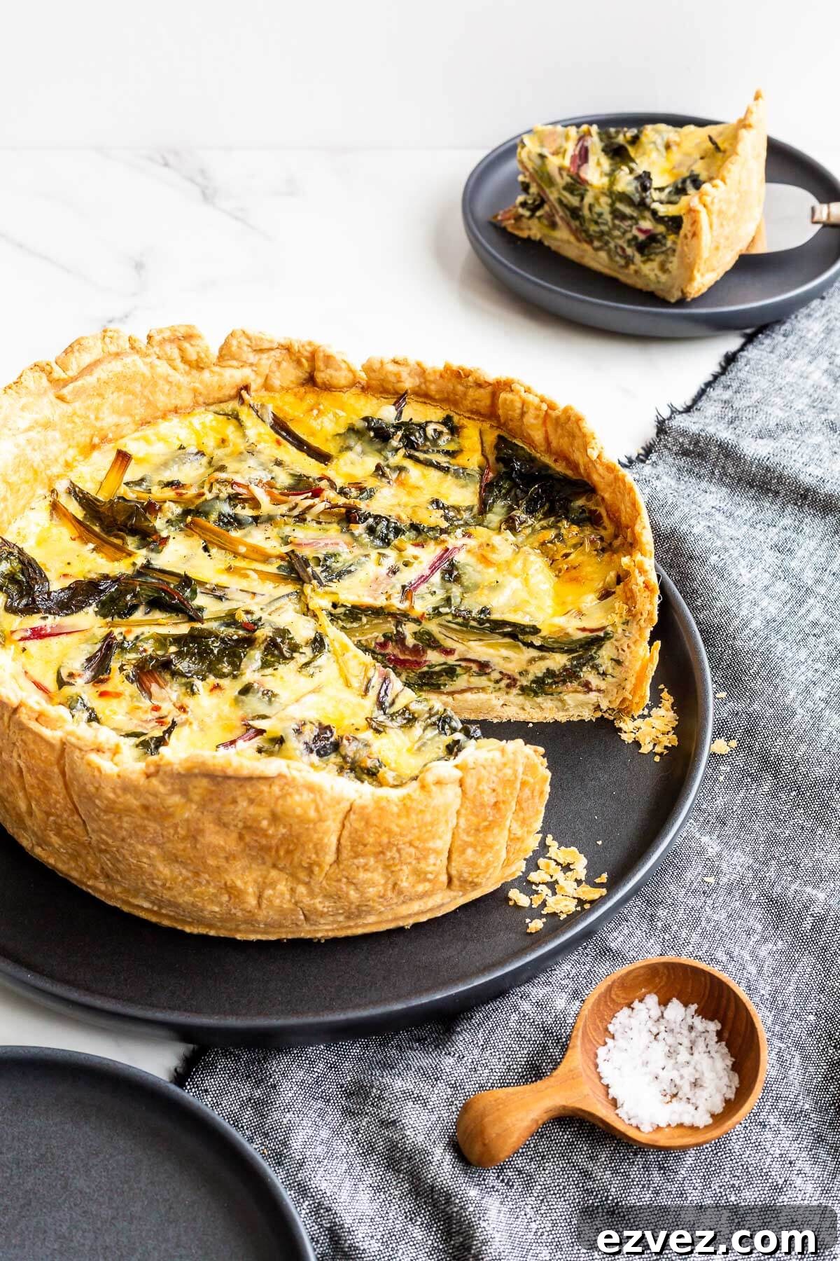 A deep dish quiche with a slice removed to a plate in the background.