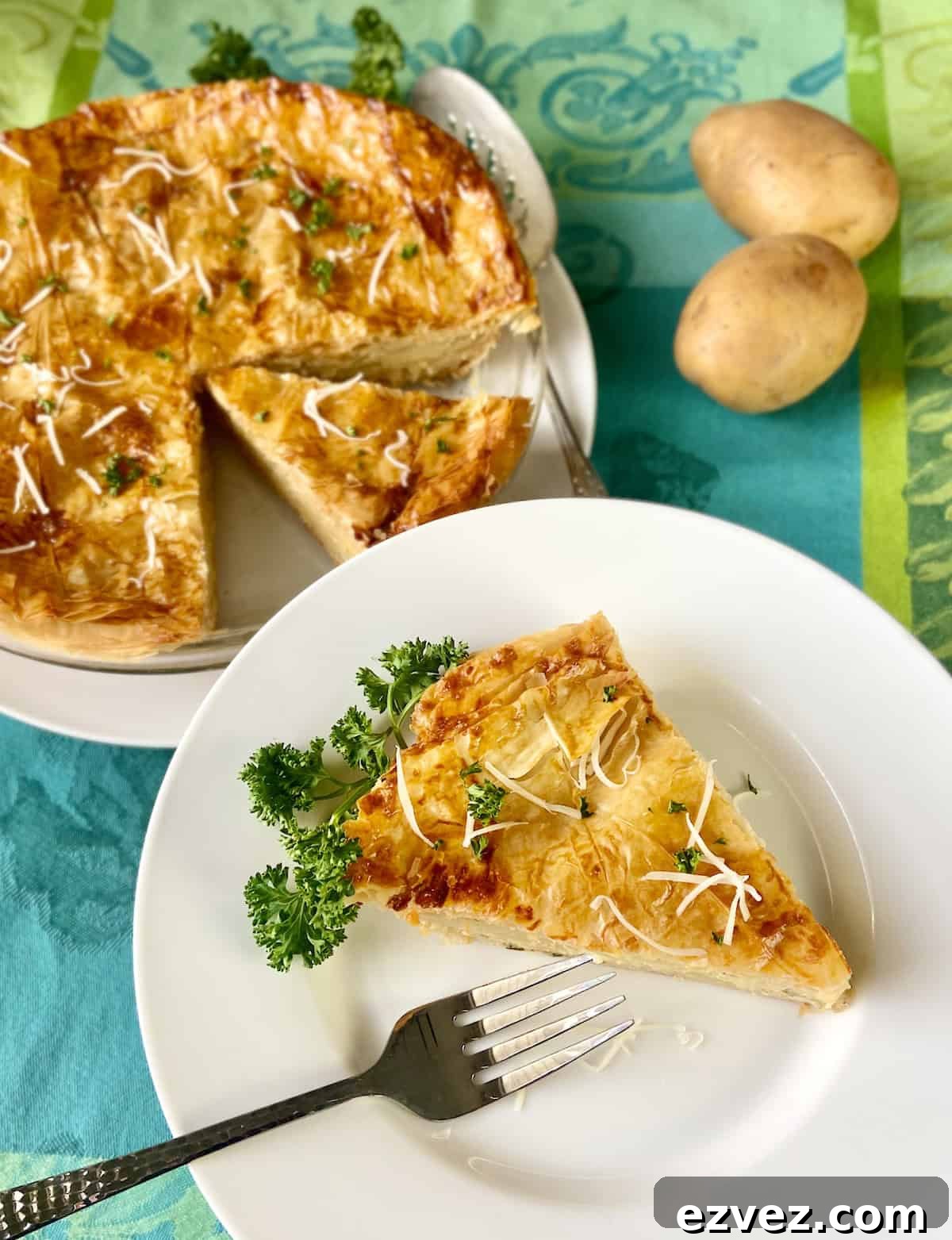 Slice of potato pie on white plate with fork.