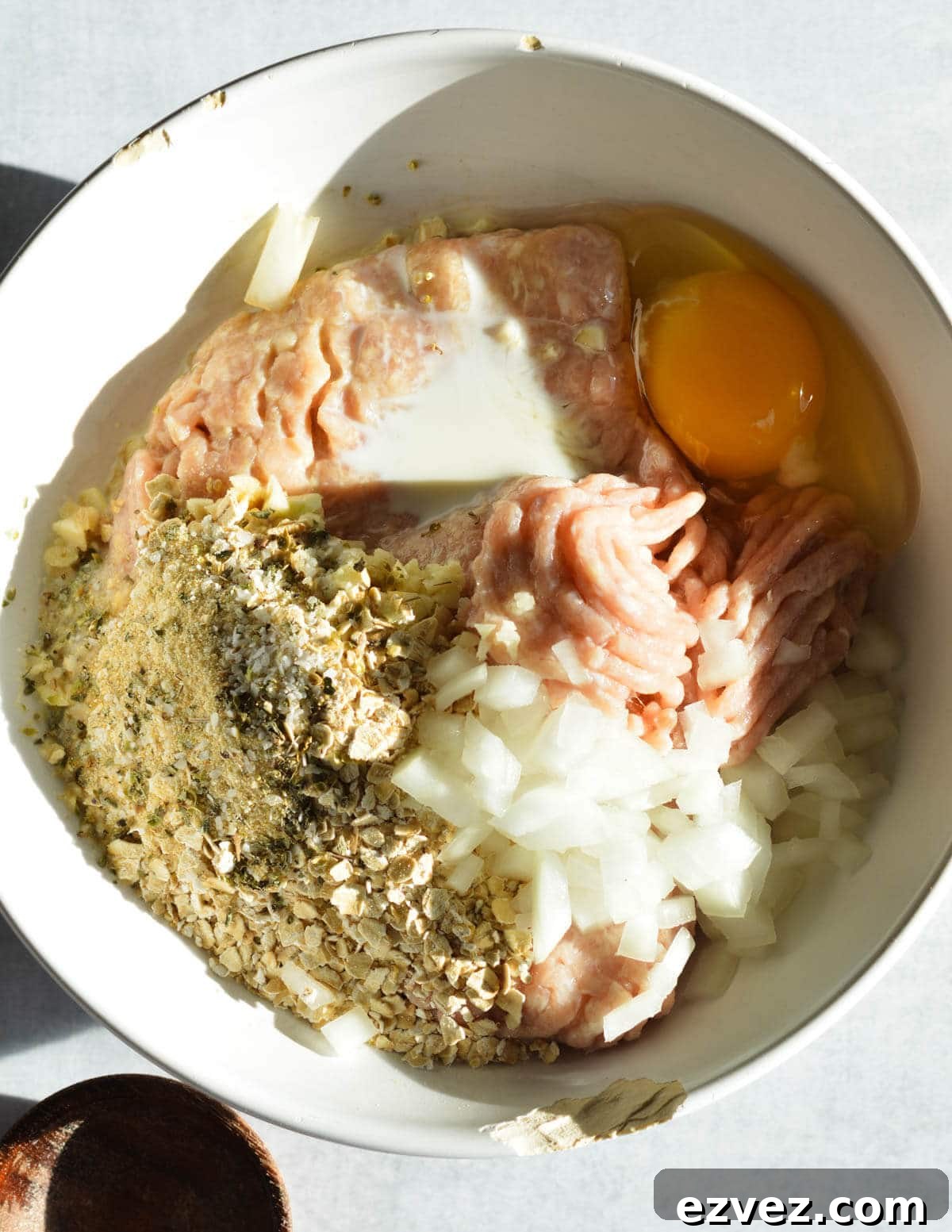 ground chicken, onion, egg, spices, and milk in a bowl. 