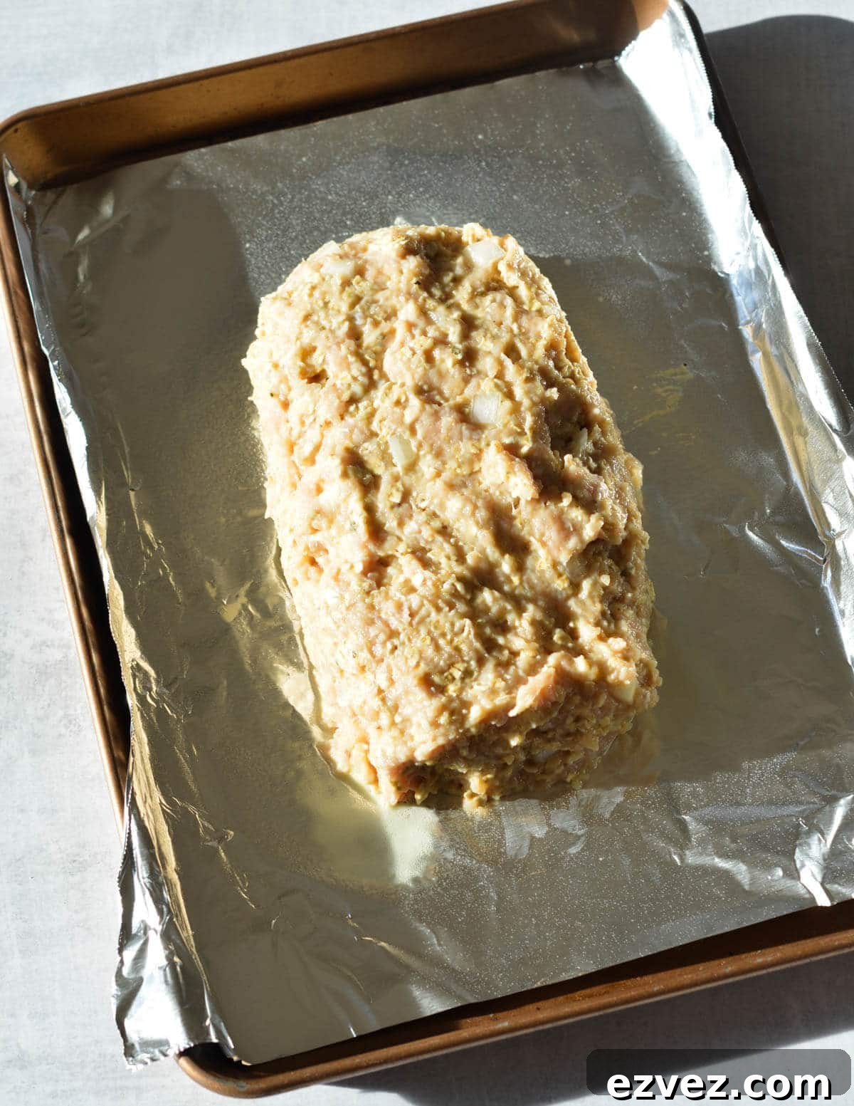 raw chicken meatloaf on a sheet pan with aluminum foil. 