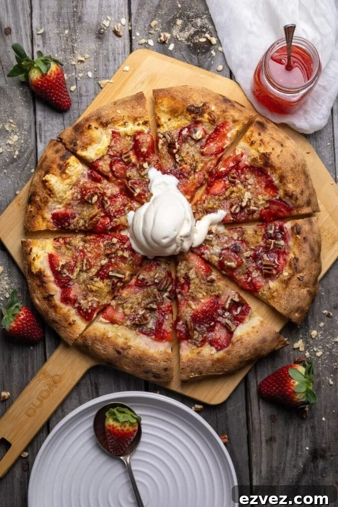 Sourdough Strawberry Crumble Pizza Recipe for Summer Gatherings 2 A sourdough strawberry crumble pizza topped with vanilla ice cream and sliced into 8 slices. There is a small jar of strawberry sauce and some fresh strawberries in the photo too.