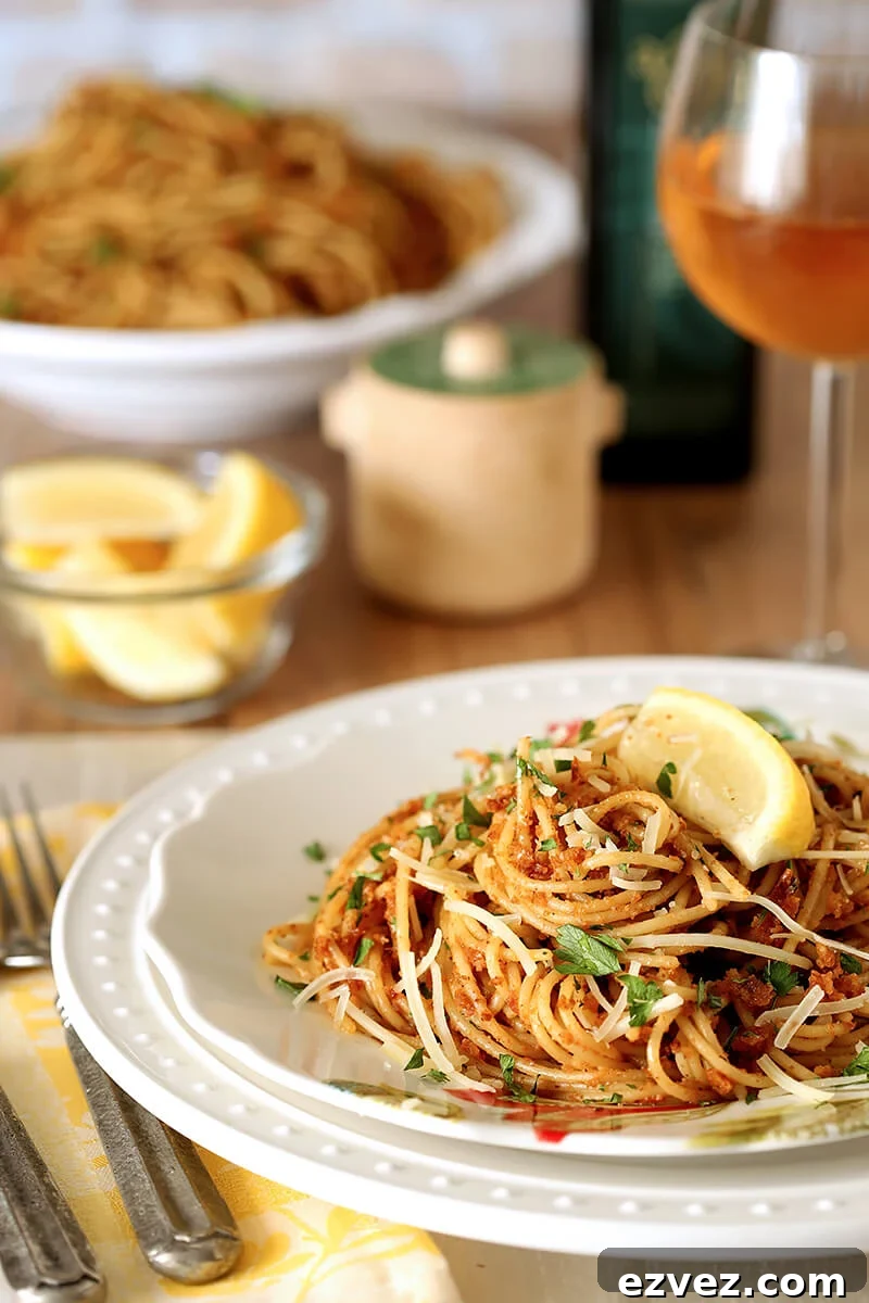 Pasta with Sun-Dried Tomato and Roasted Almond Pesto Served on a White Plate with Lemon Garnish