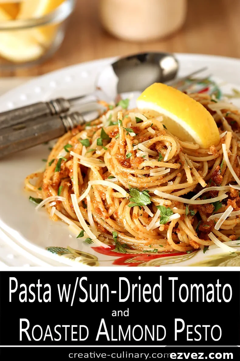 Pasta with Sun-Dried Tomato and Roasted Almond Pesto Garnished with Lemon and Basil on White Decorated Plate