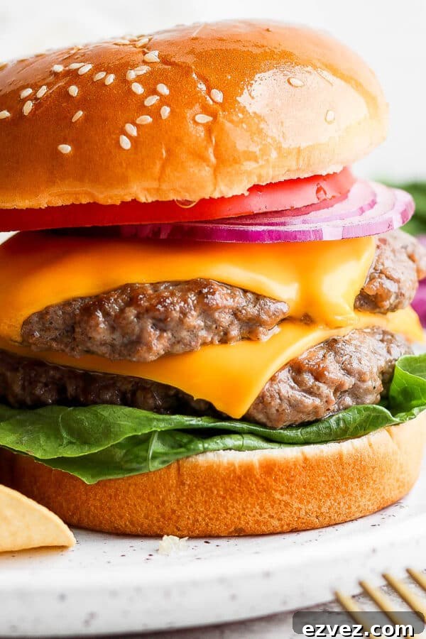 A double butter burger on a bun with lettuce, cheese, onion and tomato.