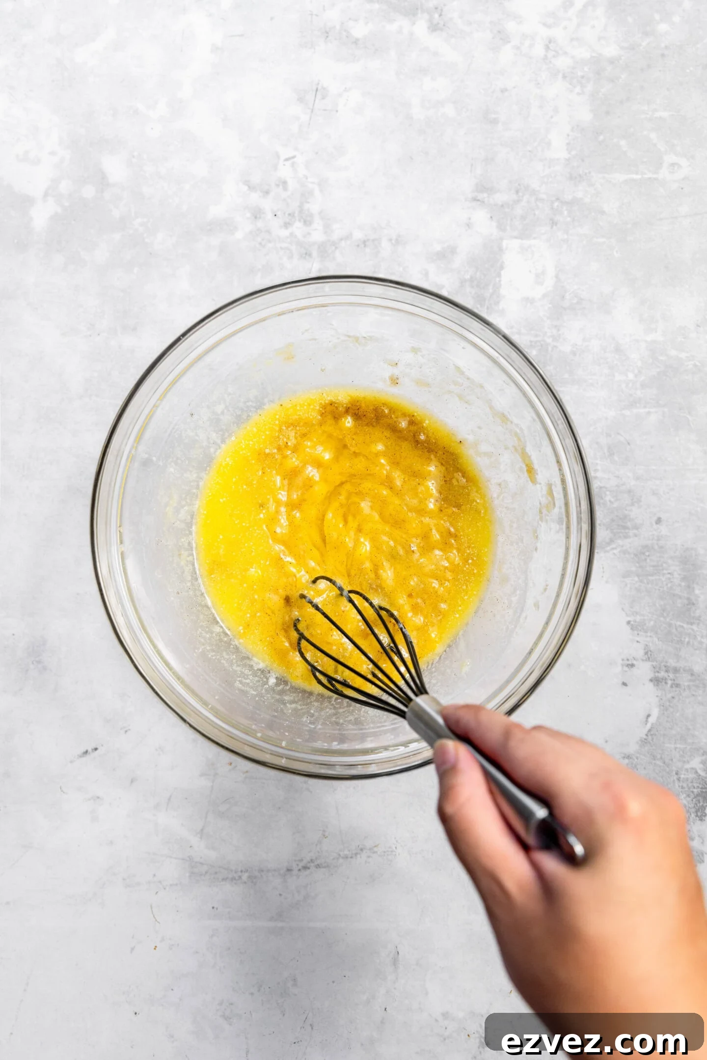 Melted butter and one egg being whisked into the mashed bananas