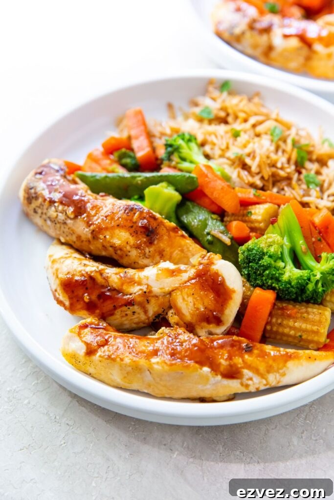 teriyaki chicken tenders, fried rice and teriyaki vegetables on a white plate