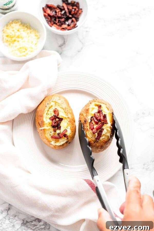 Crispy Air Fryer Baked Potatoes in 30 Minutes 5 Baked potatoes topped with cheese and bacon and served on a white plate.