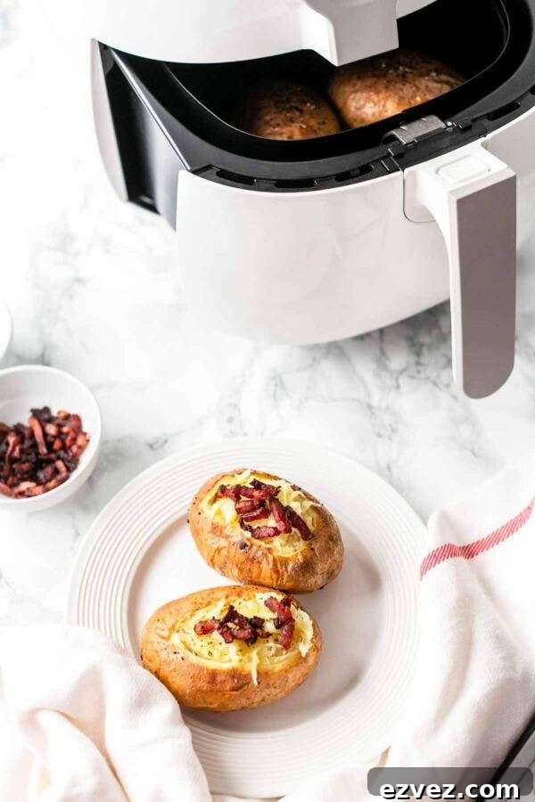 Crispy Air Fryer Baked Potatoes in 30 Minutes 6 Two baked potatoes on a white plate.