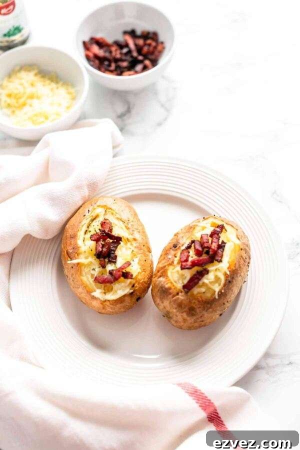 Crispy Air Fryer Baked Potatoes in 30 Minutes 7 Close up of baked potatoes with a topping of shredded cheese and crispy bacon.