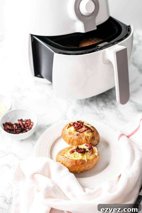 Crispy Air Fryer Baked Potatoes in 30 Minutes 9 Air Fryer baked potatoes with melted cheese and bacon bits served on a white plate.