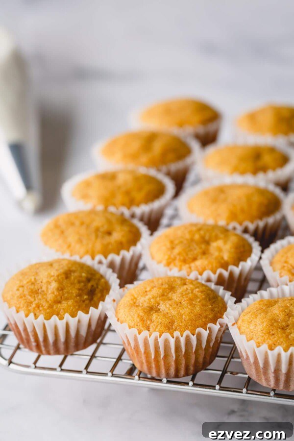 Unfrosted mini pumpkin cupcakes on a cooling rack.