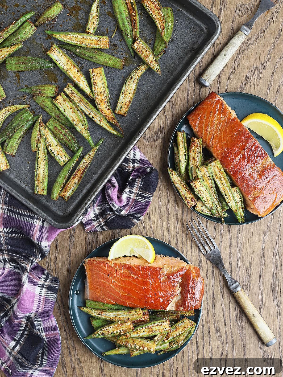 Two salmon fillets served alongside roasted okra on blue plates.