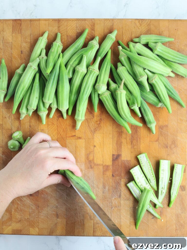 Hands slicing okra pod in half.
