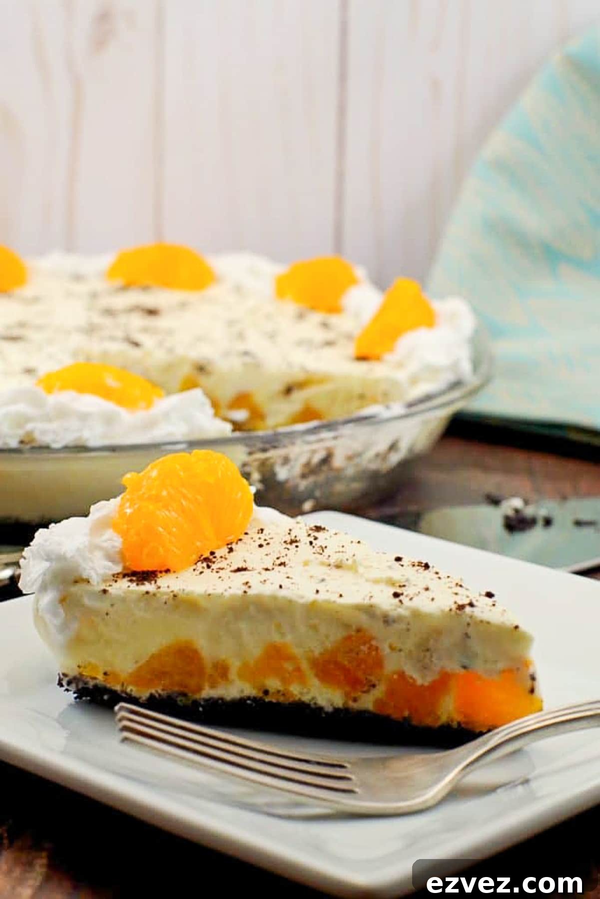 Piece of Orange Creamsicle pie (dairy-free) on white plate with whole pie in background