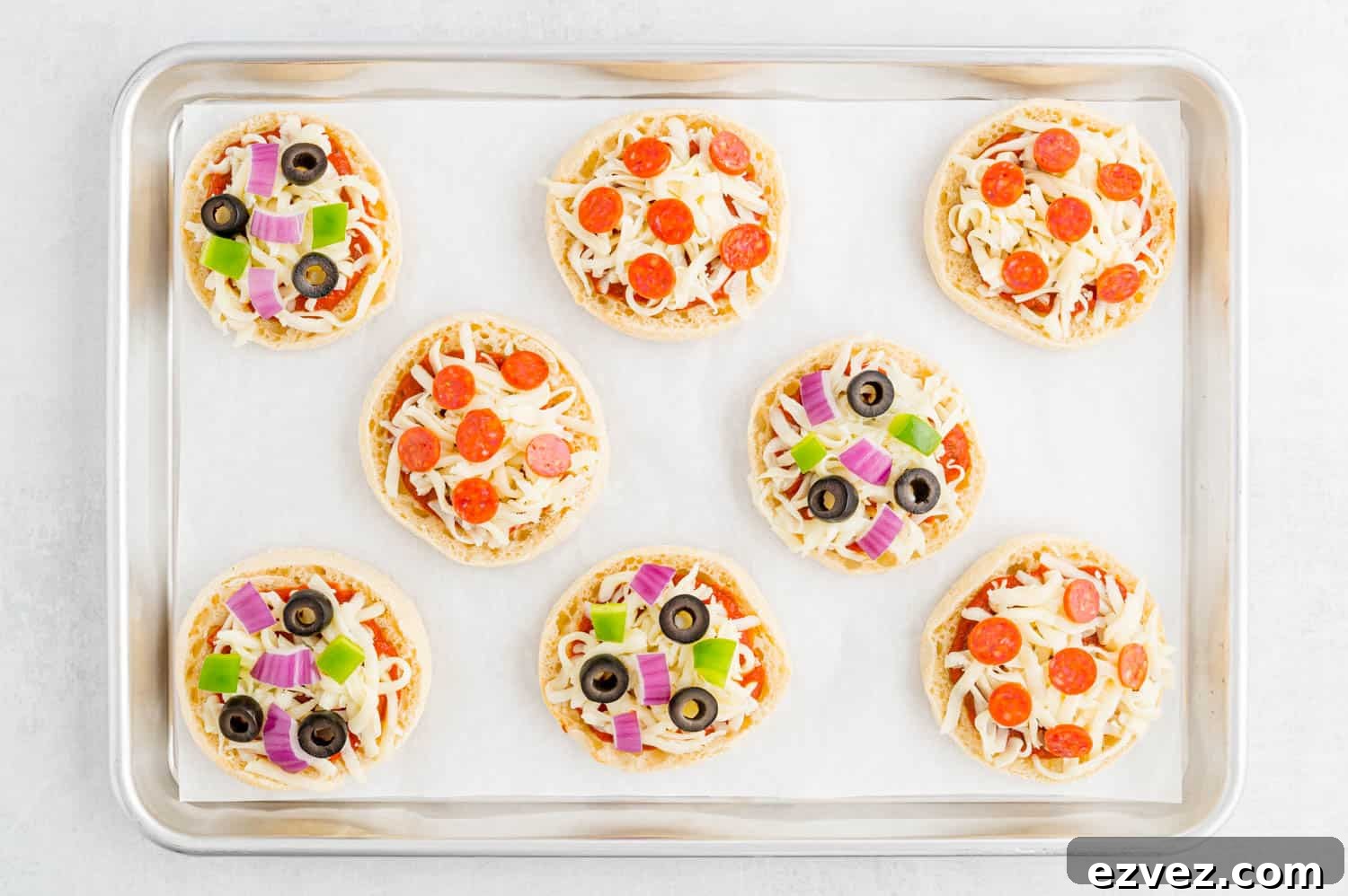 Quick English Muffin Pizzas for Fast Weeknight Dinner 5 Uncooked english muffin pizzas on a sheet pan.