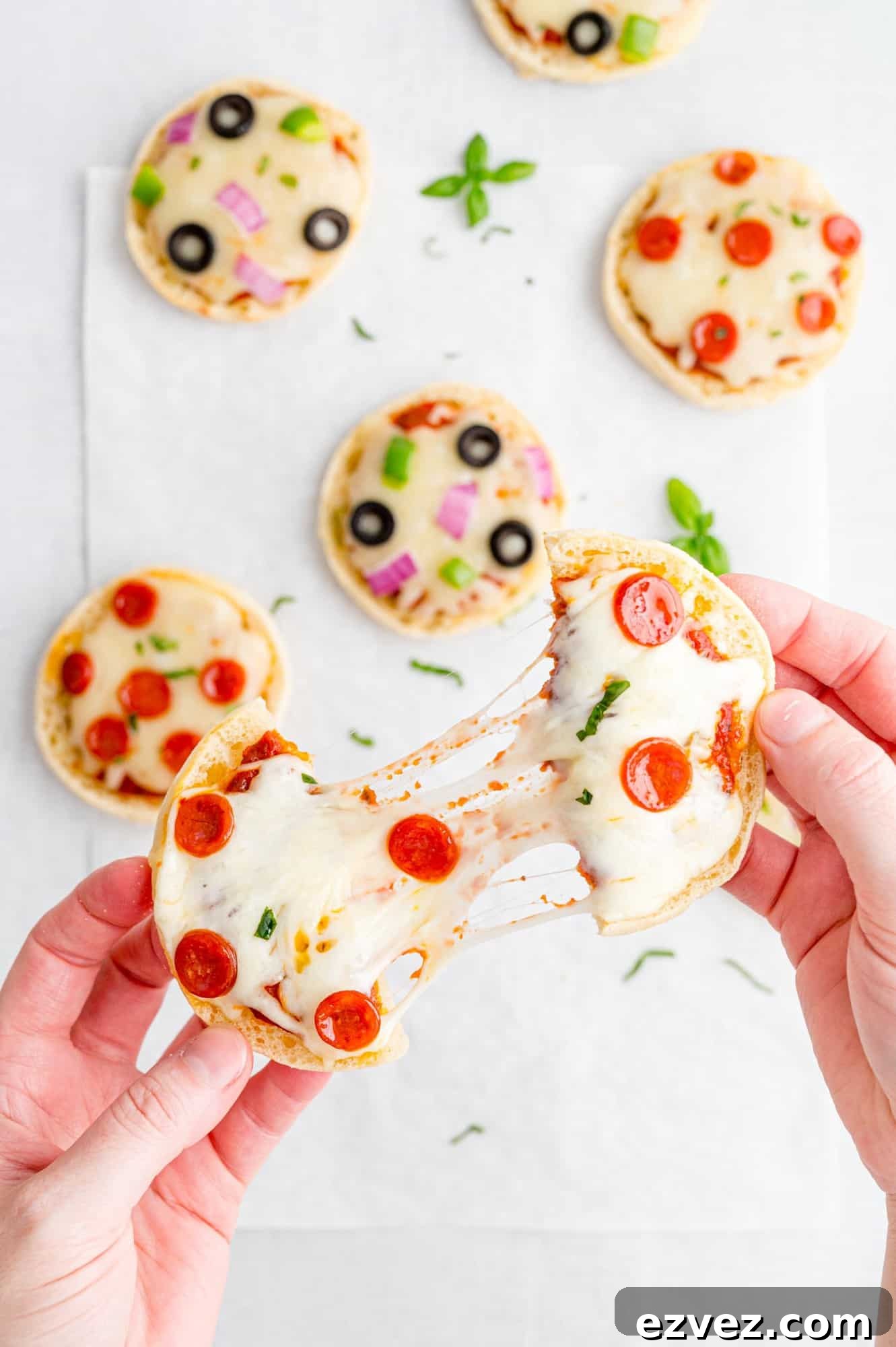 Quick English Muffin Pizzas for Fast Weeknight Dinner 6 Two halves of an english muffin pizza being pulled apart, connected by cheese.