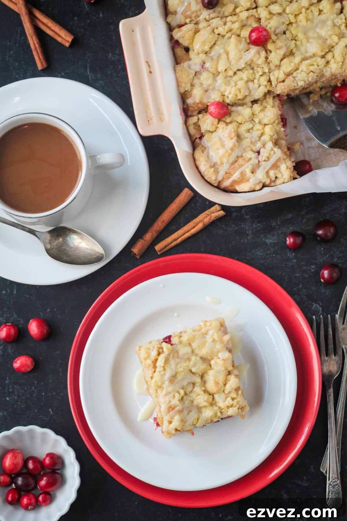 Slice of cake on a plate next to a cup of coffee and the baking dish of more cake.