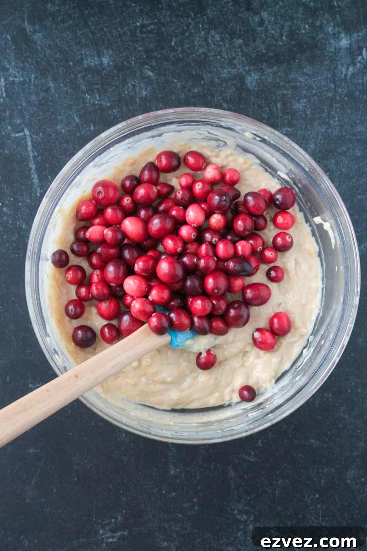 Fresh cranberries added to the cake batter in a mixing bowl.