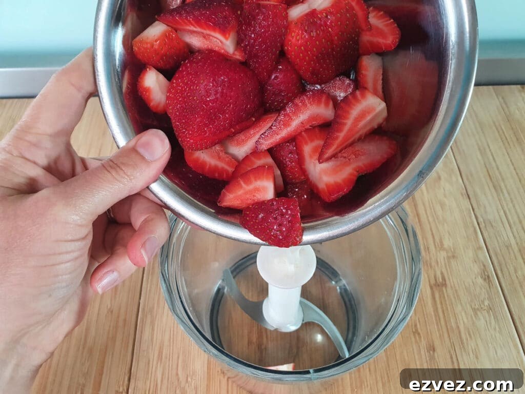 adding strawberries to food processor for sauce.