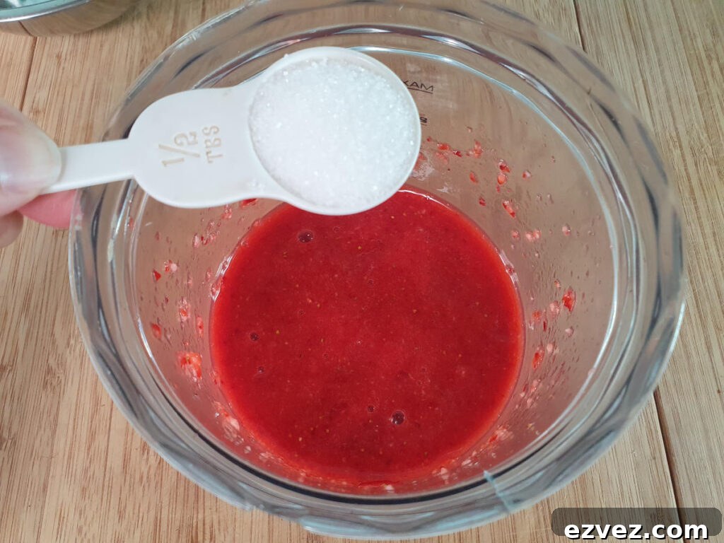 adding sugar to strawberry sauce in food processor.