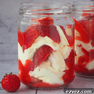 Two jars of Eton mess with fresh strawberries on the side.