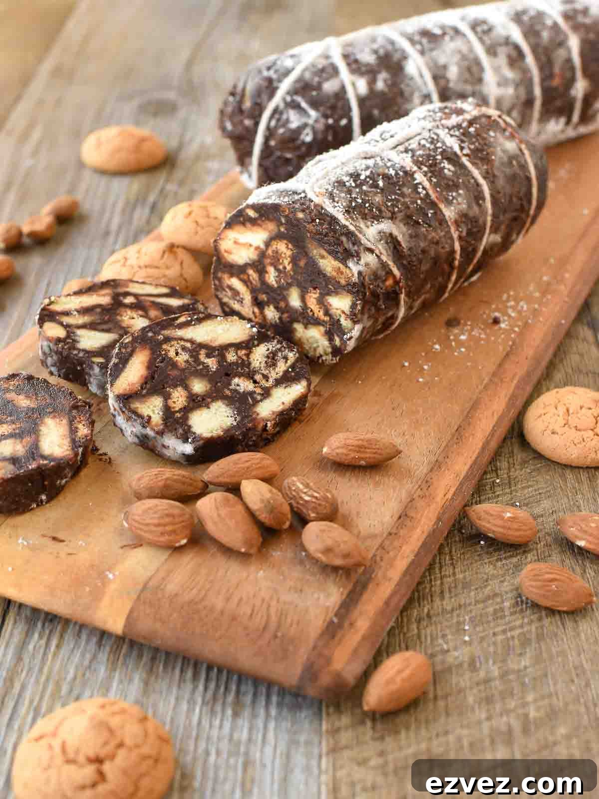 Chocolate salami on wooden board with three slices cut.
