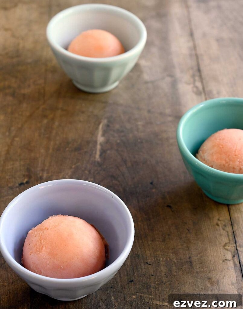 Scoops of watermelon sorbet in small cups on a wooden table.