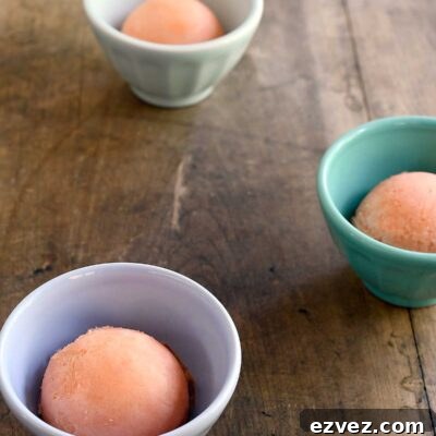 Scoops of watermelon sorbet in small cups on a wooden table.