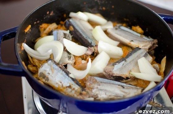 Canned mackerel pie and onion is added to kimchi in a pot.