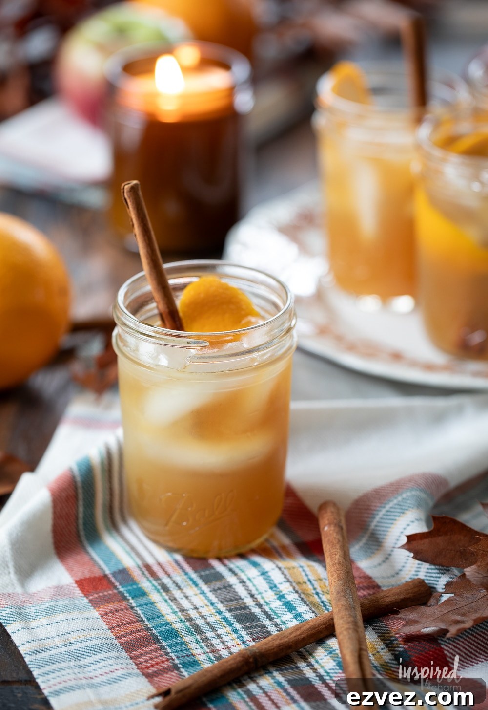 apple cider whiskey sour cocktail set in a cozy fall setting with a candle.