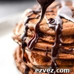Close up of drizzling chocolate ganache on a stack of double chocolate peppermint protein pancakes.