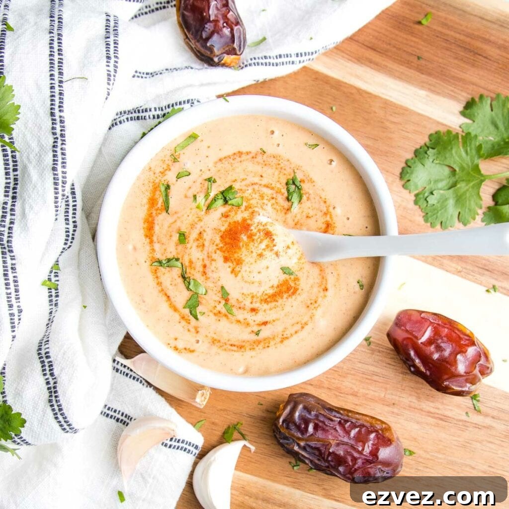 small white bowl filled with chipotle salad dressing that's light orange with extra chipotle powder sprinkled on top and swirled around with fresh chopped cilantro.
