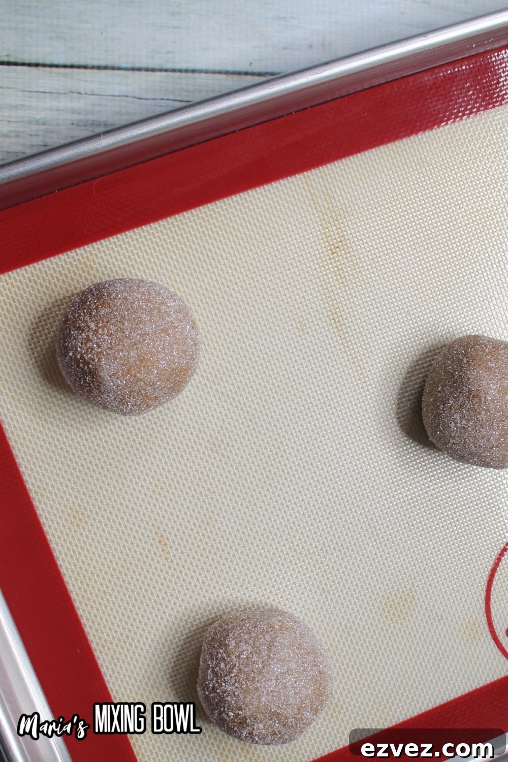 cookie dough balls on a silicone lined baking sheet