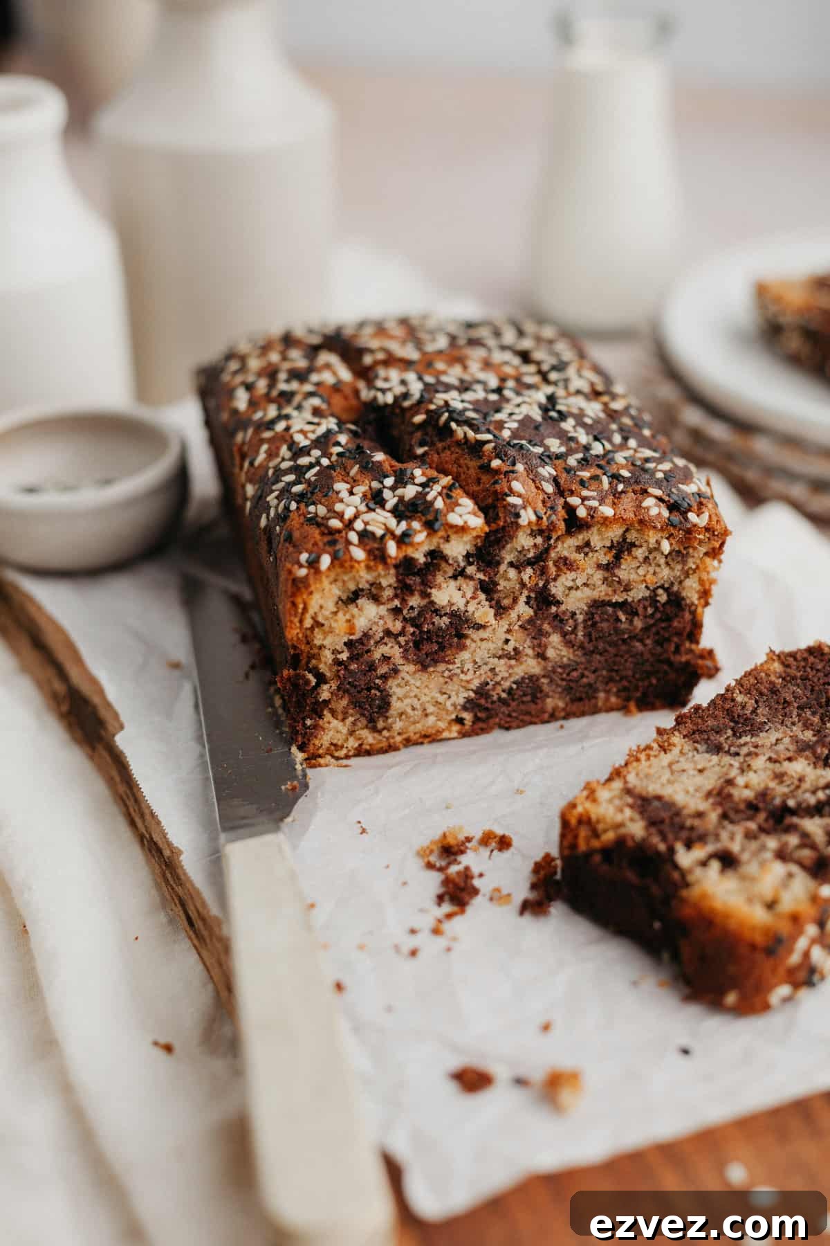 a swirled tahini banana bread on parchment paper, one slice has been cut off.