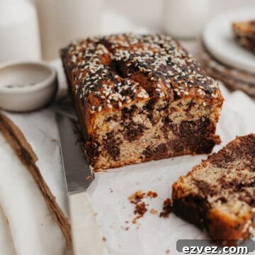 a swirled tahini banana bread on parchment paper, one slice has been cut off.
