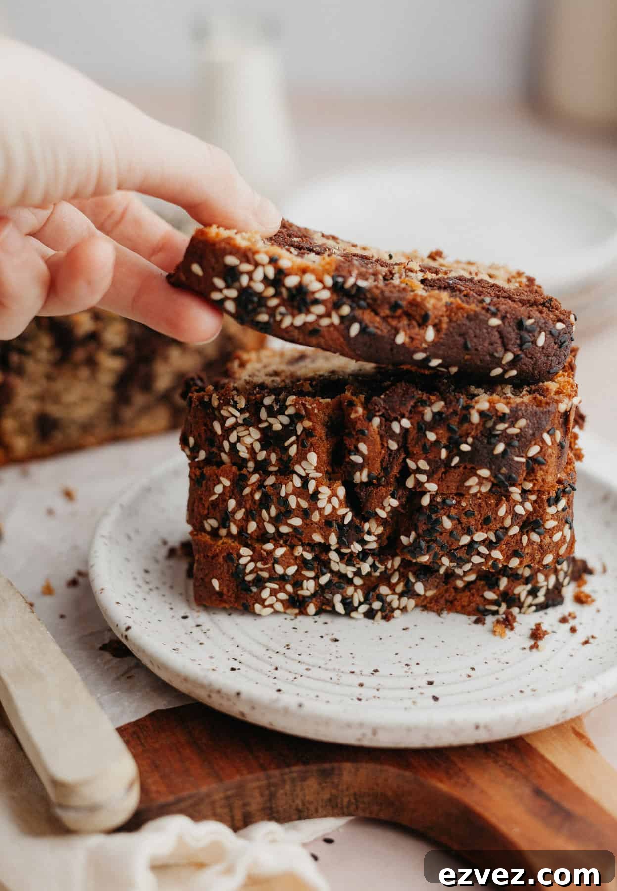 a stack of banana bread slices on a small plate, a hand is lifting one slice off.