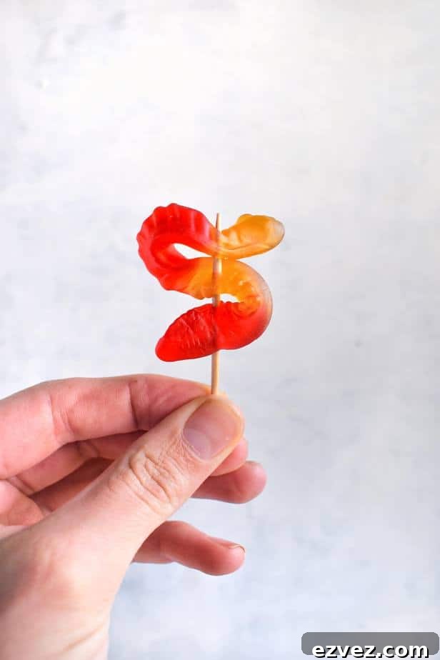 hand holding gummy worm on toothipck