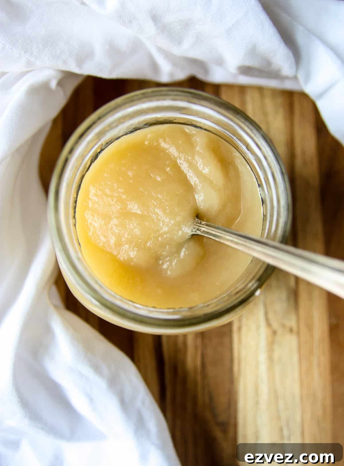 A jar of homemade applesauce with a silver spoon.