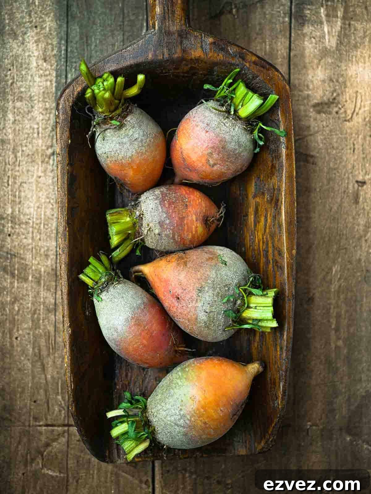 Overhead of raw golden beets on a wooden surface.