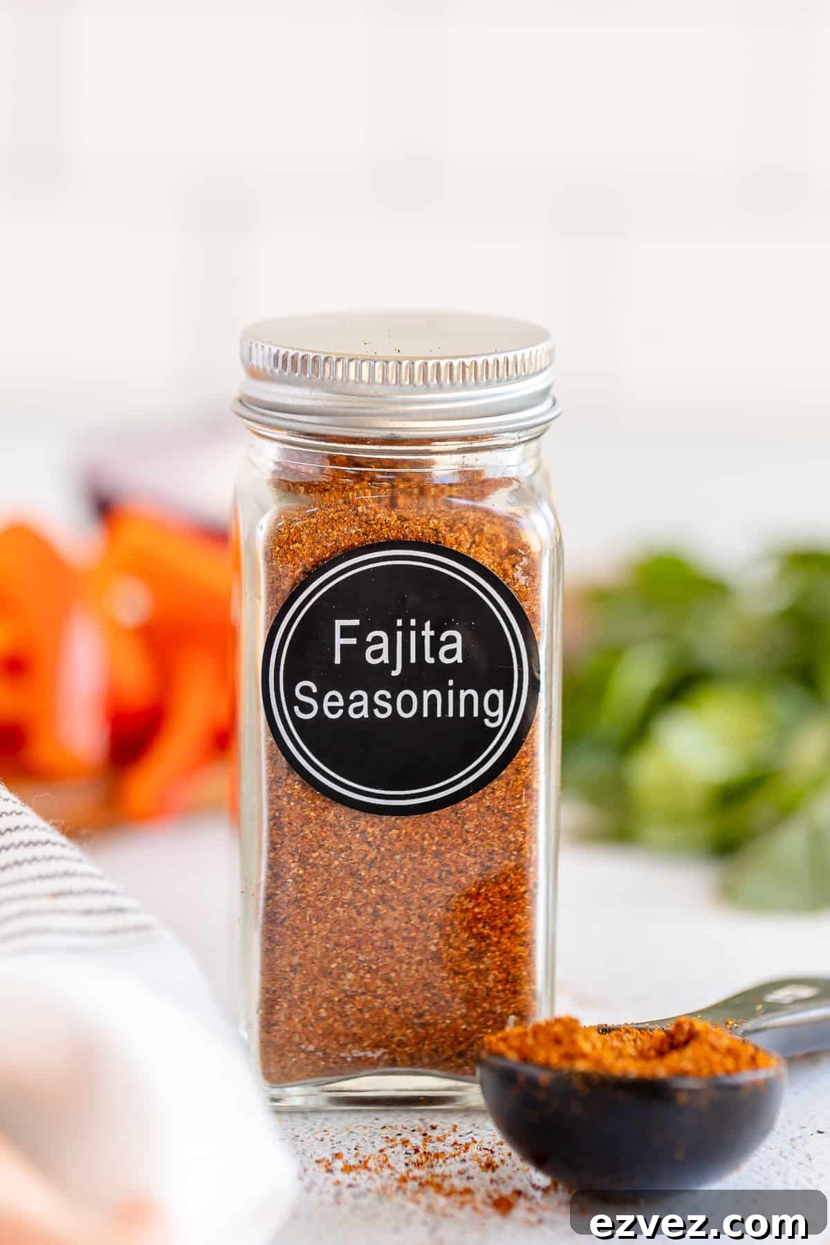 Homemade Fajita Seasoning Blend for Authentic Mexican Flavor 2 A spice bottle with a label that reads Fajita Seasoning and filled with brown spice next to a measuring spoon full of the spice.