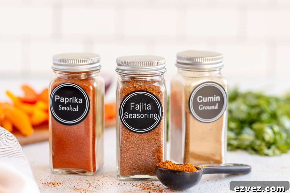 Homemade Fajita Seasoning Blend for Authentic Mexican Flavor 4 Two spice jars on either side of a jar of fajita seasoning with a measuring spoon lying in front.